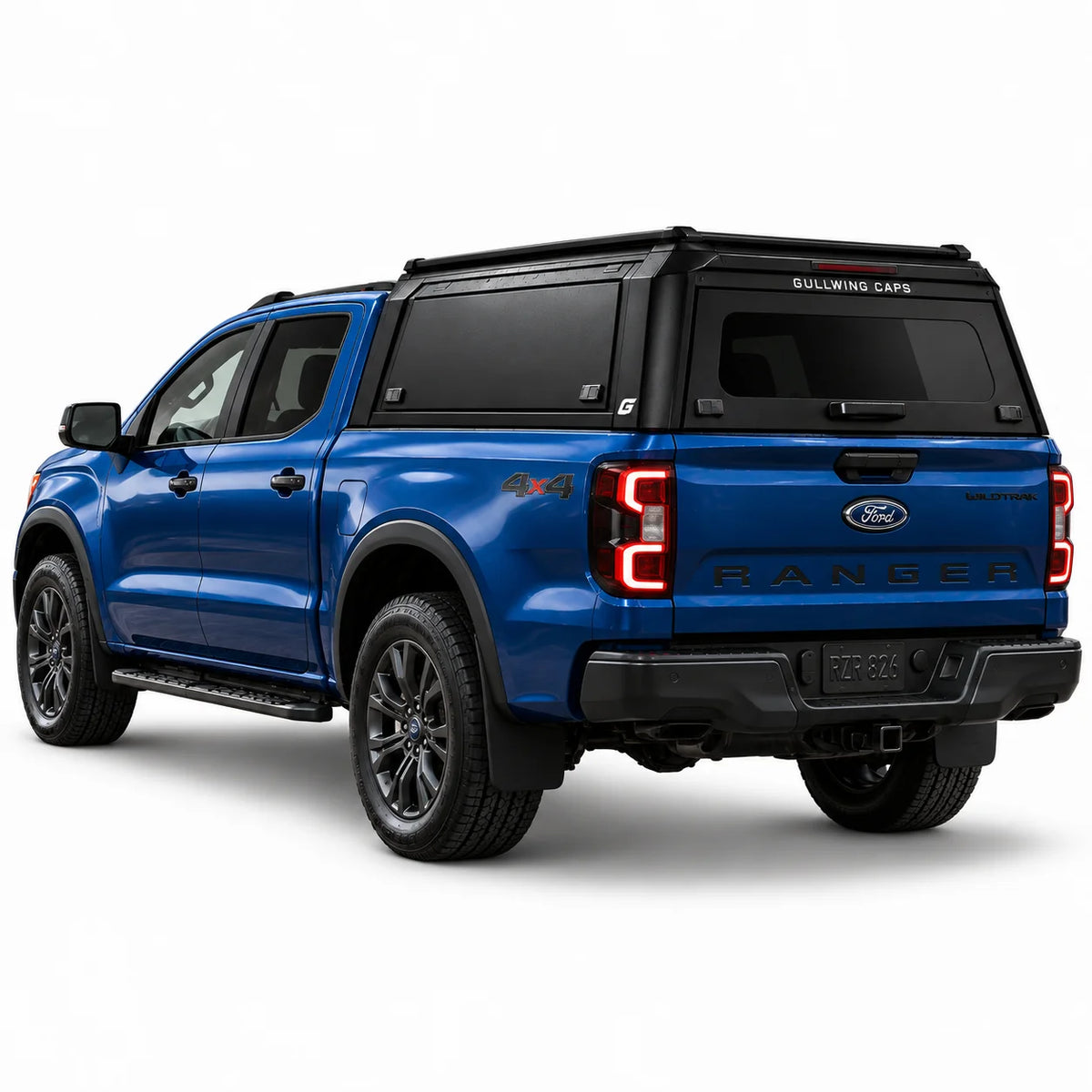 A blue Ford Ranger pickup truck shown from a rear three-quarter angle, fitted with a black Gullwing Caps aerowing truck canopy, set against a plain white studio background.