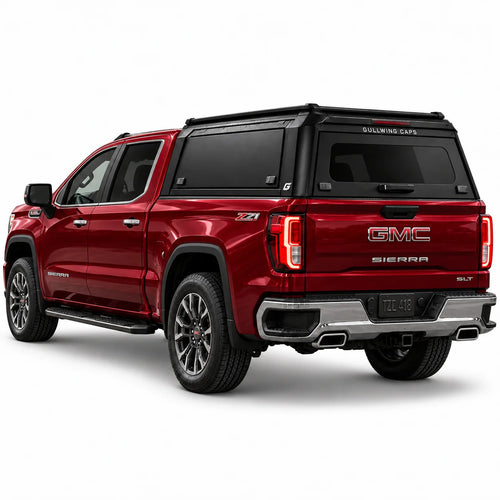 A red GMC Sierra 1500 pickup truck shown from a rear three-quarter angle, fitted with a black Gullwing Caps aerowing truck canopy, set against a plain white studio background.